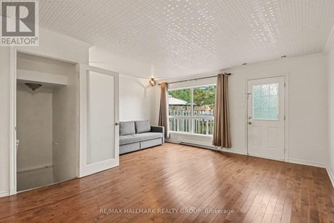 A spacious room with wooden flooring and white walls.