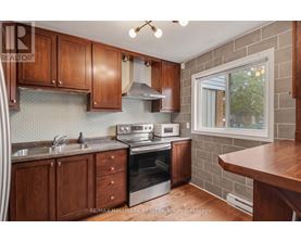 A kitchen with wooden cabinets and a brick wall.