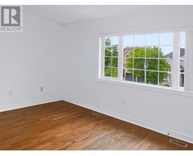 A room with a window showing a view of houses and trees outside.