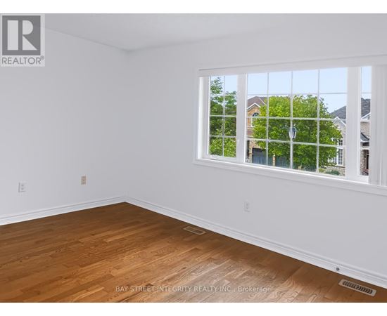 A room with a window showing a view of houses and trees outside.