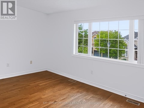 A room with a window showing a view of houses and trees outside.