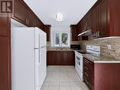 A kitchen with brown cabinets and a white refrigerator.