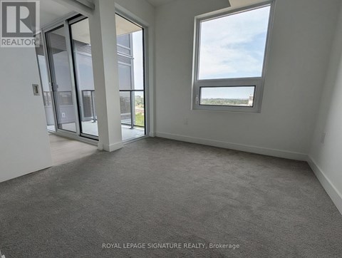 A room with a carpet floor and a window showing a view of the sky.