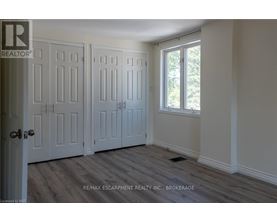 A room with a door and a window with a view of trees outside.