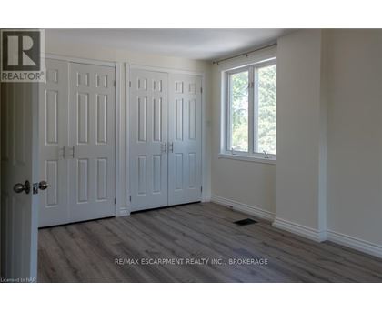 A room with a door and a window with a view of trees outside.