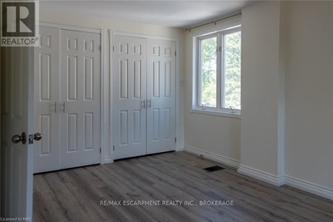 A room with a door and a window with a view of trees outside.