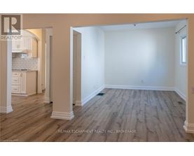 A spacious room with wooden flooring and white walls.