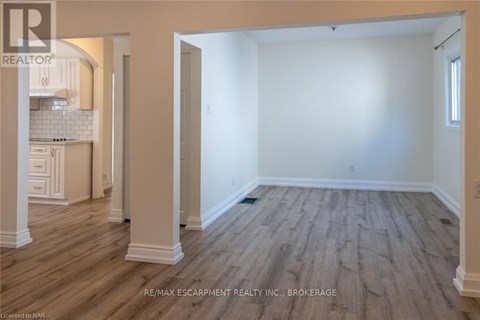 A spacious room with wooden flooring and white walls.