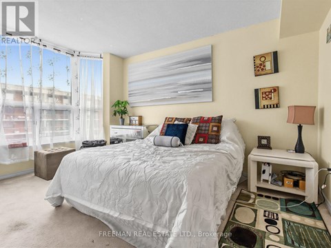 A bedroom with a large bed and a window with curtains.