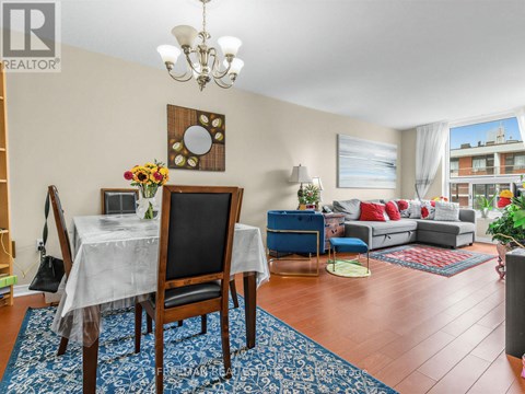 A dining room with a table set for two and a couch in the background.
