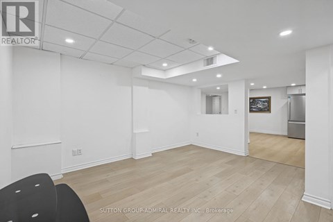 A spacious room with a white ceiling and wooden flooring.