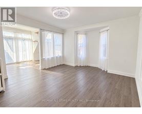 A spacious room with wooden flooring and white walls.