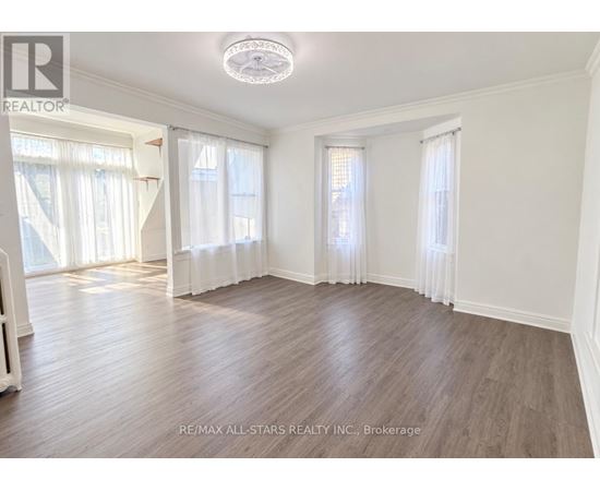 A spacious room with wooden flooring and white walls.