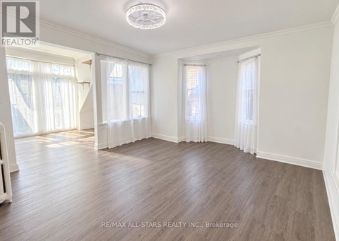 A spacious room with wooden flooring and white walls.