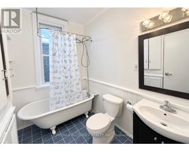 A white toilet sits next to a white bathtub in a bathroom.