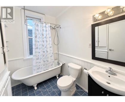 A white toilet sits next to a white bathtub in a bathroom.