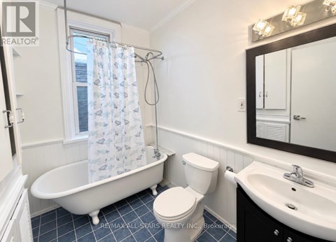 A white toilet sits next to a white bathtub in a bathroom.