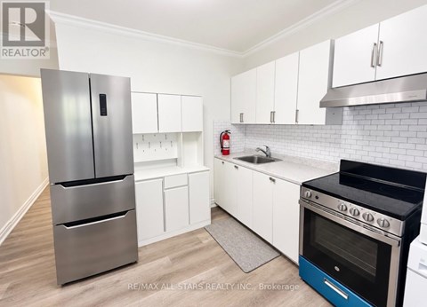 A kitchen with white cabinets and a stainless steel refrigerator.