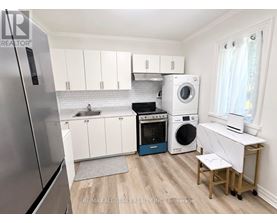 A small kitchen with a refrigerator, oven, washing machine, and dryer.