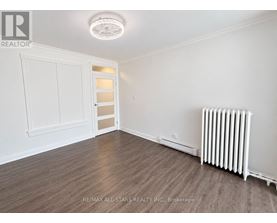 A room with a white ceiling light, a white door, and a white radiator on the wall.