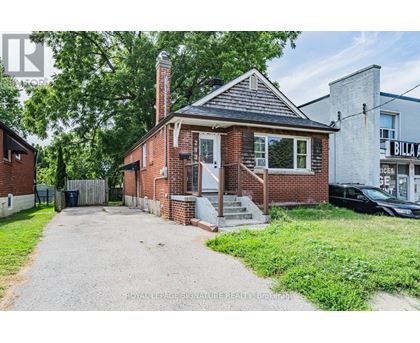 A brick house with a porch and a driveway in front.