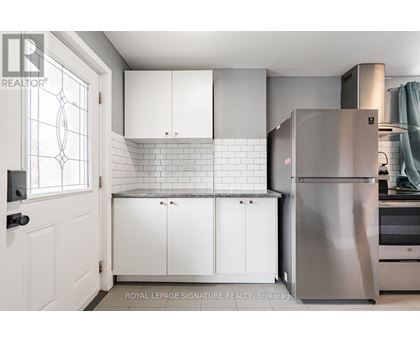 A kitchen with white cabinets and a stainless steel refrigerator.