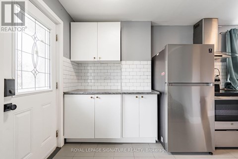 A kitchen with white cabinets and a stainless steel refrigerator.