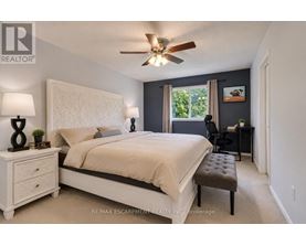 A bedroom with a large bed, a ceiling fan, and a window with a view of trees.