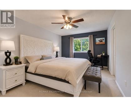 A bedroom with a large bed, a ceiling fan, and a window with a view of trees.