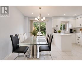 A modern dining room with a glass table and black chairs.