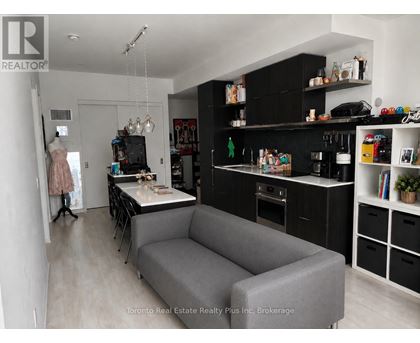 A grey couch is in the middle of a kitchen and living room.