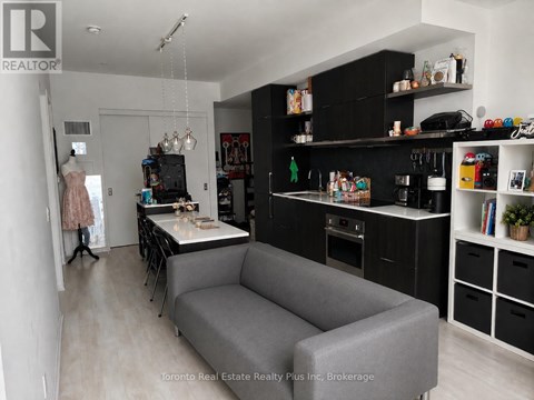 A grey couch is in the middle of a kitchen and living room.