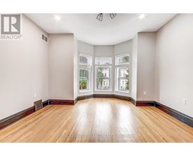 A spacious room with wooden floors and large windows.