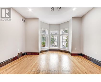 A spacious room with wooden floors and large windows.