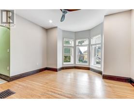 A room with a ceiling fan and a window with a view of a building.