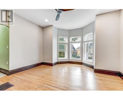 A room with a ceiling fan and a window with a view of a building.