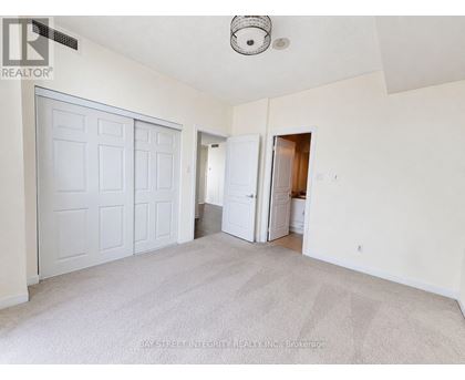 A white bedroom with a carpeted floor and a ceiling fan.