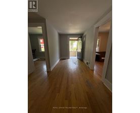 A long hallway with wood floors and white walls.
