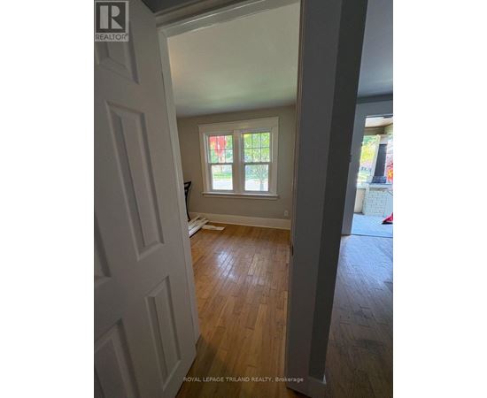 A room with a white door and wooden flooring.