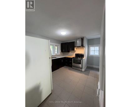 A kitchen with a white refrigerator, black cabinets, and a stove top oven.
