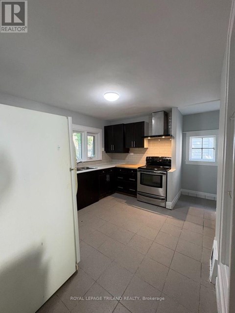 A kitchen with a white refrigerator, black cabinets, and a stove top oven.