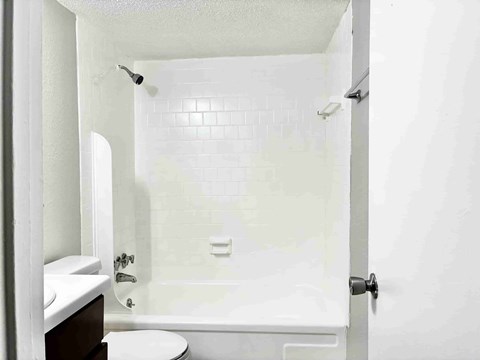 A white bathroom with a toilet, sink, and bathtub.
