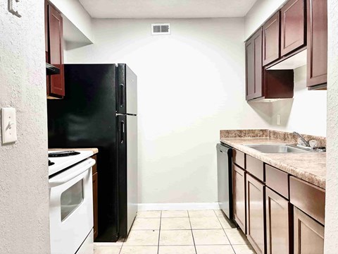 A kitchen with a black refrigerator and white stove.