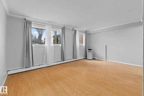 A room with wooden flooring and a window with curtains.