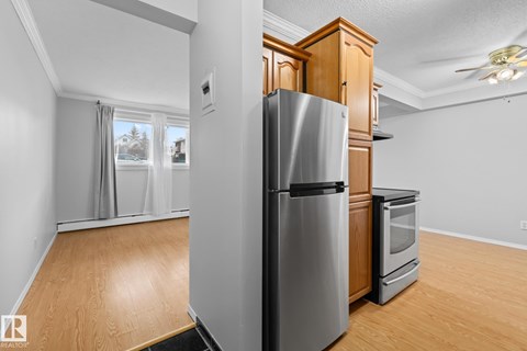 A kitchen with a stainless steel refrigerator and wooden cabinets.