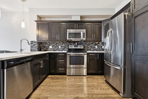 A modern kitchen with dark wood cabinets and stainless steel appliances.