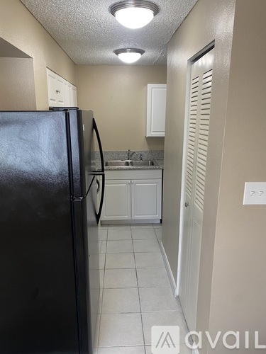 A kitchen with a black refrigerator and white cabinets.