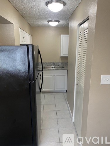 A kitchen with a black refrigerator and white cabinets.