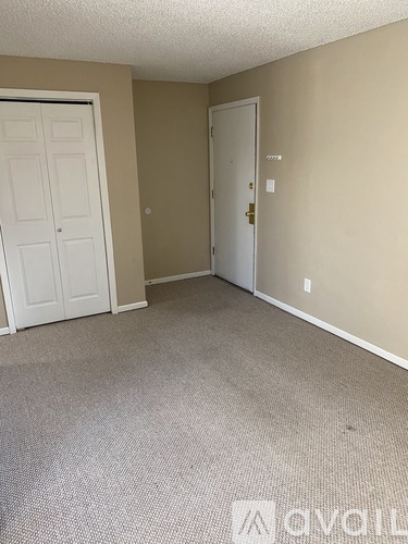 A carpeted room with two doors, one of which is closed.