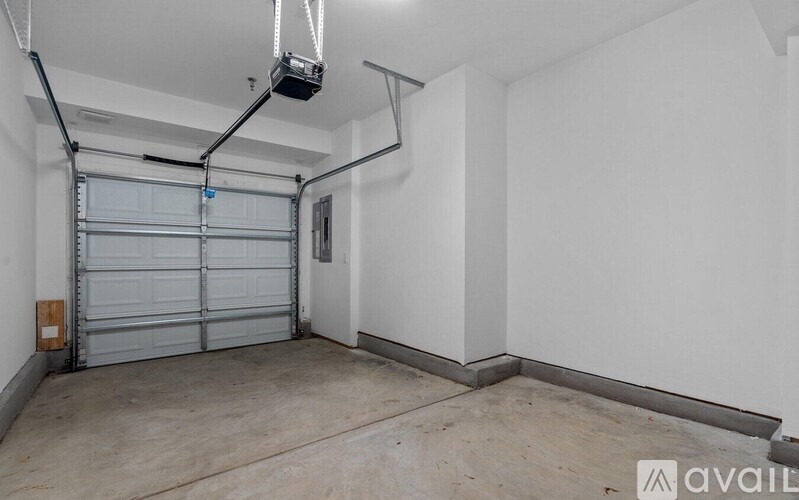 A spacious garage with a white wall and a grey door.